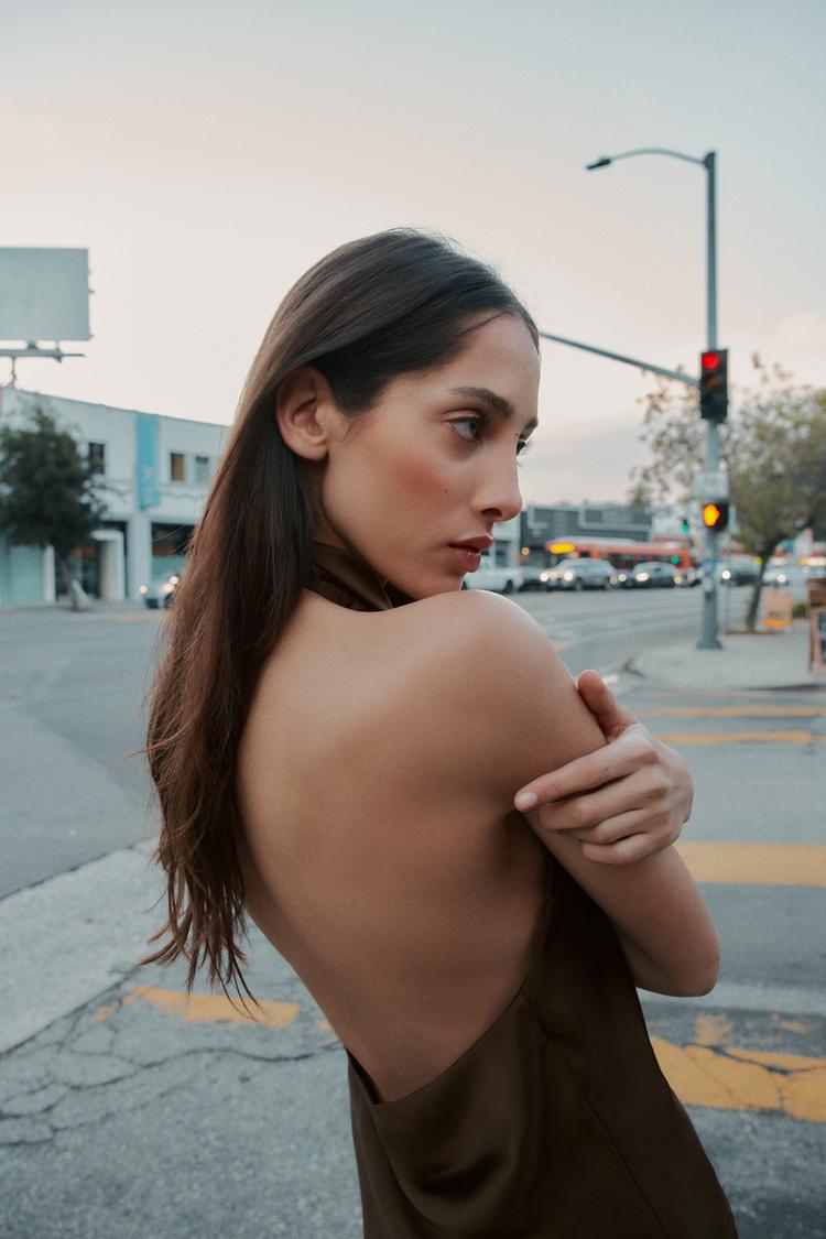 Black satin backless camisole by SAINT CLAIRE, featuring a sleek, smooth fabric and elegant backless design.